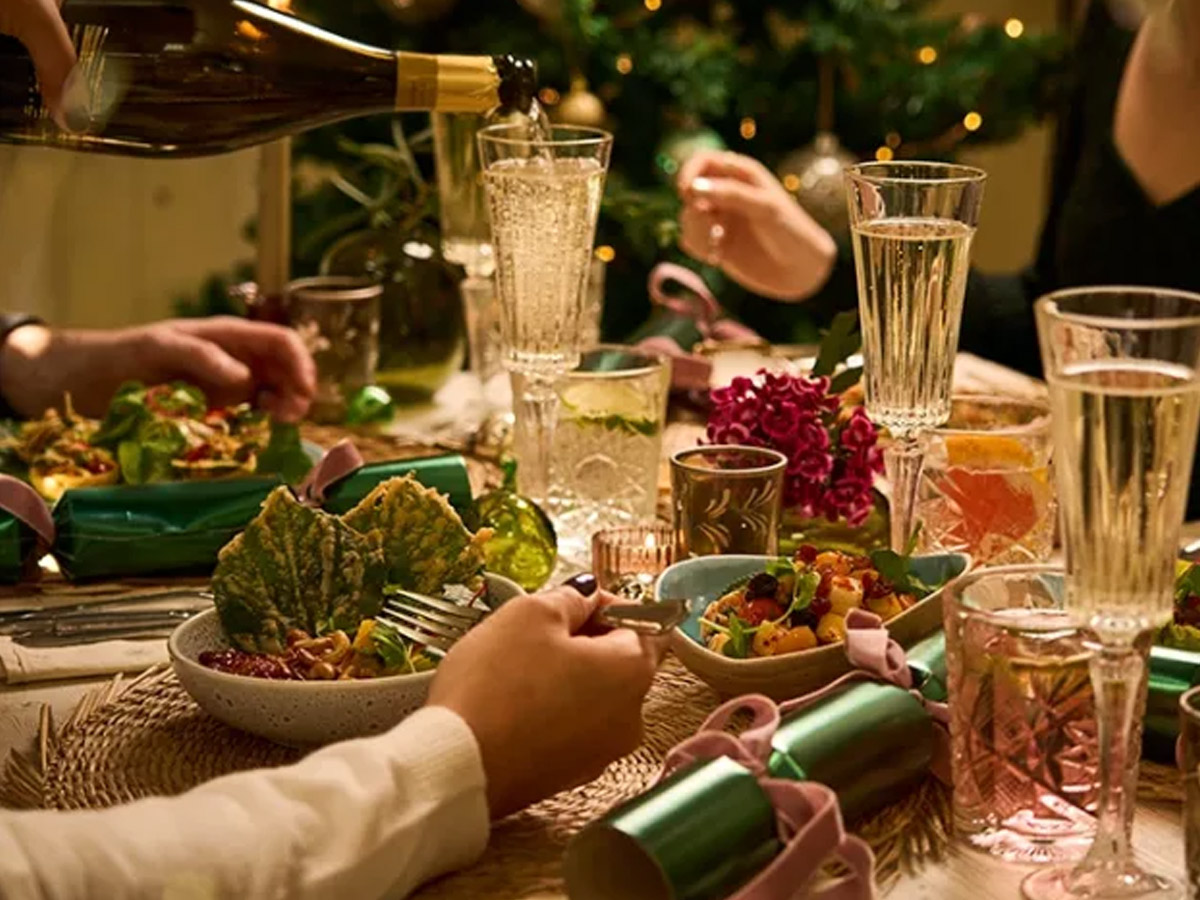 A candlelit Christmas table with crackers, sharing plates and sparkling wine