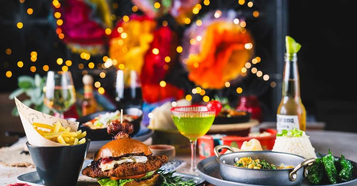 Festive plates and cocktails at Las Iguanas beneath string lights and piñatas