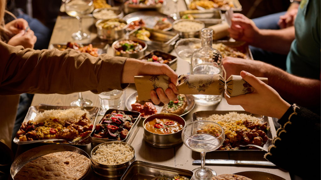 A sharing feast of Indian dishes in tiffin tins at Mowgli, with a cracker being pulled across the table