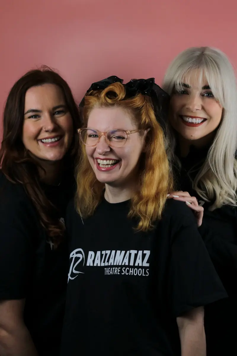 Three Razzamataz Theatre Schools team members smiling against a pink background