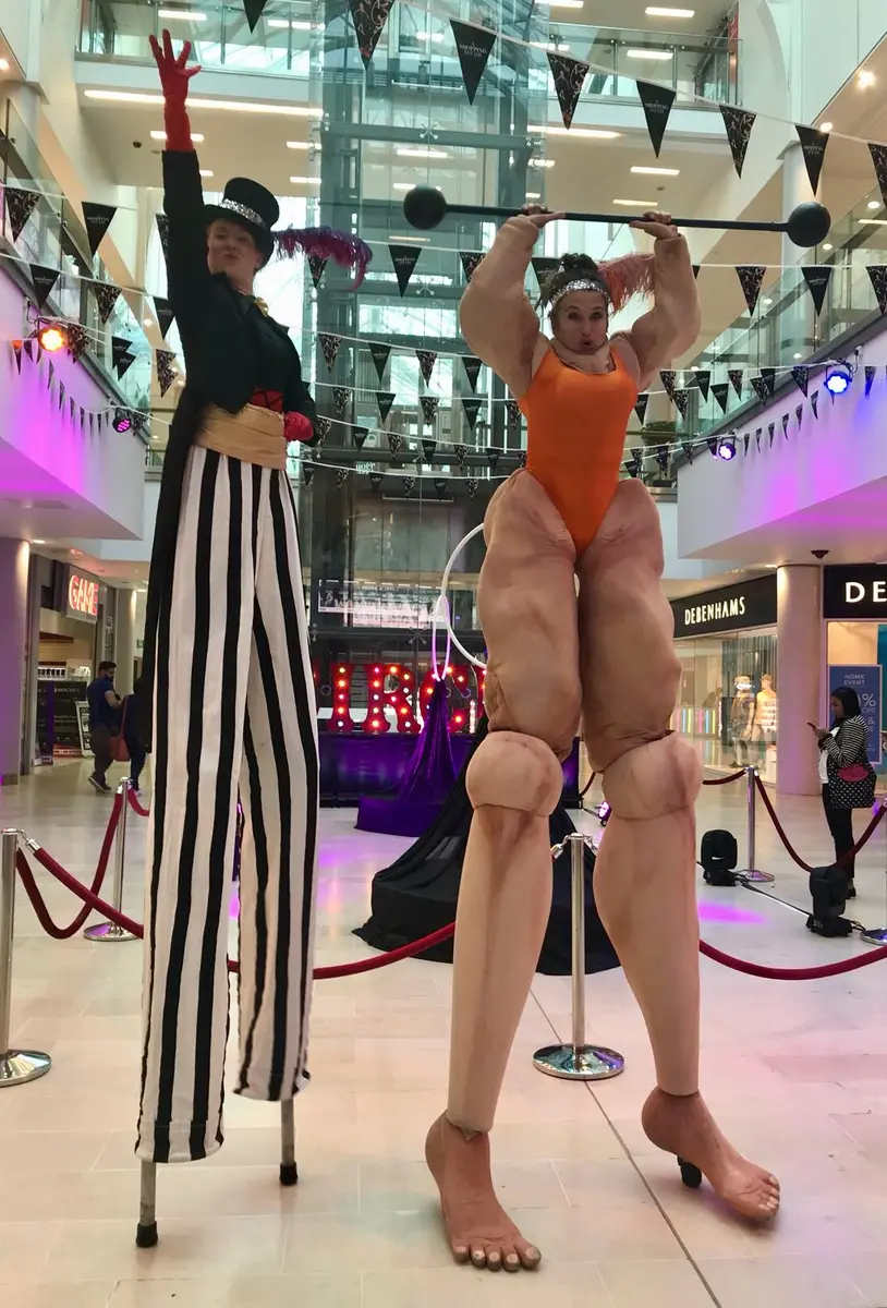 The Circus Ringmistress and Strong Woman performing together on stilts