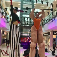 The Circus Ringmistress and Strong Woman performing together on stilts